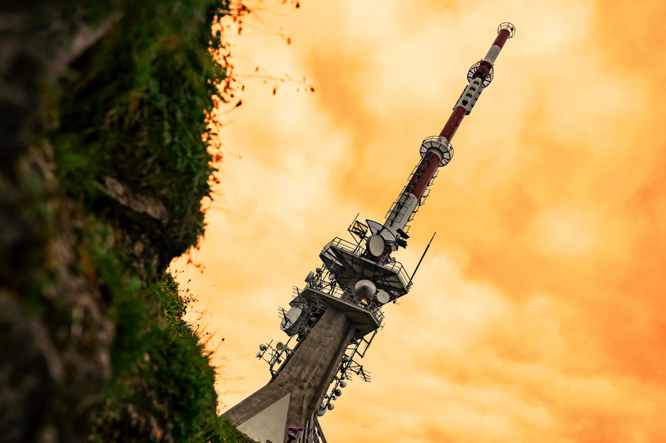 Une antenne penchée sur un ciel orangé, allégorie. Image iGeneration, photo de base Alin Andersen sur Unsplash.